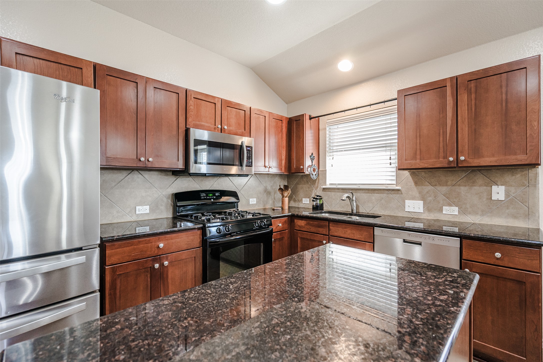 2404 Christoff Loop Austin, TX 78748 - Photo 3 of 24 a kitchen with stainless steel appliances granite countertop wooden cabinets a stove top oven a sink and dishwasher