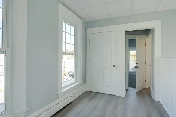 a view of an empty room with wooden floor and a window