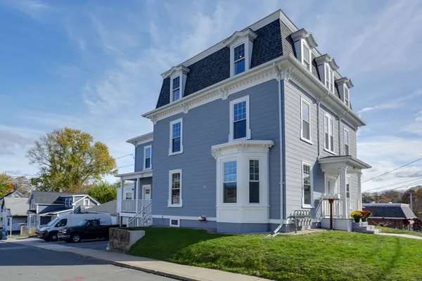 a front view of a building with a yard and car parked
