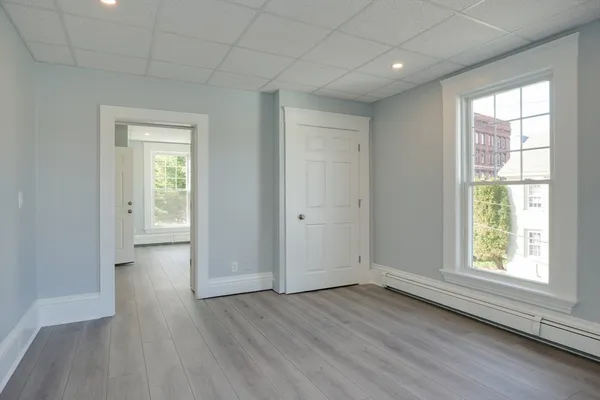 an empty room with wooden floor and windows