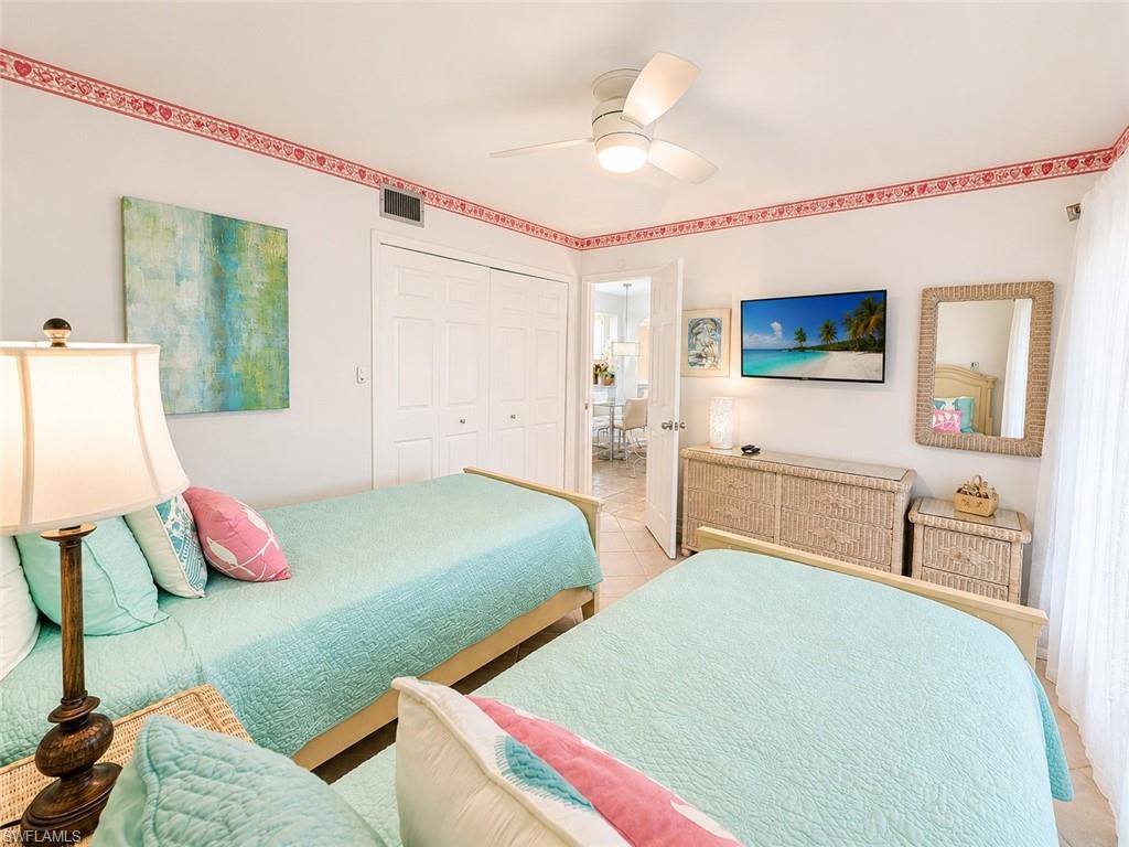 600 Neapolitan Way, Unit 449 Naples, FL 34103 - Photo 17 of 44 Bright bedroom featuring a ceiling fan, tiled flooring, and white bi-fold closet doors