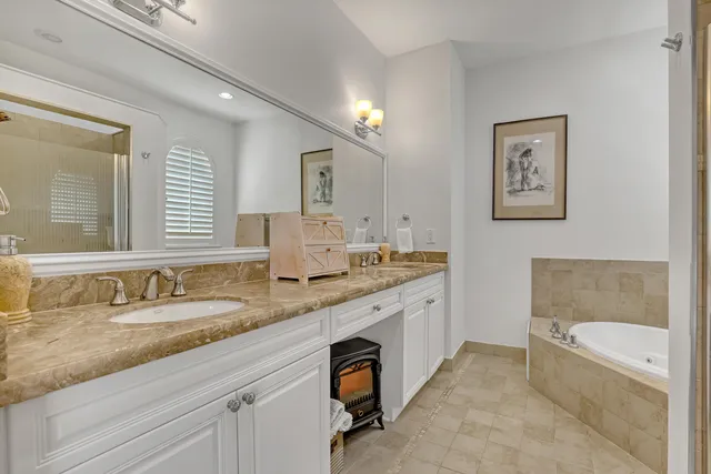 a bathroom with a granite countertop double vanity sink and a bathtub