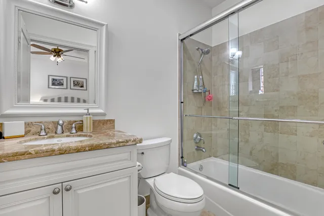 a bathroom with a granite countertop sink a mirror a bathtub and shower