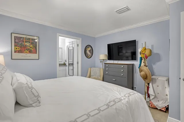 a bedroom with a bed and a flat tv screen on dresser