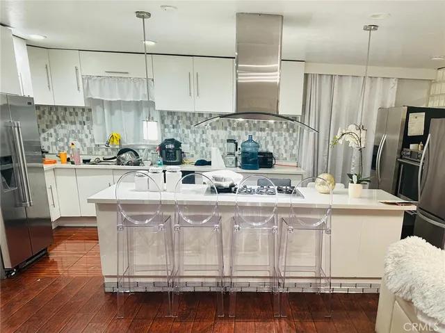 a kitchen with kitchen island granite countertop a sink a stove and refrigerator