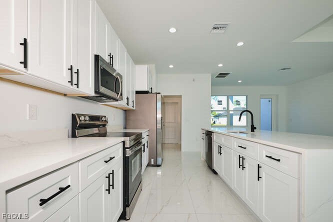 3421 55th Street West Lehigh Acres, FL 33971 - Photo 12 of 38 a kitchen with stainless steel appliances granite countertop a sink a stove and a refrigerator