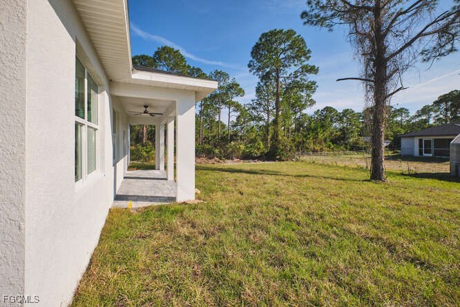 3421 55th Street West Lehigh Acres, FL 33971 - Photo 36 of 38 a view of a white house with a small yard and potted plants