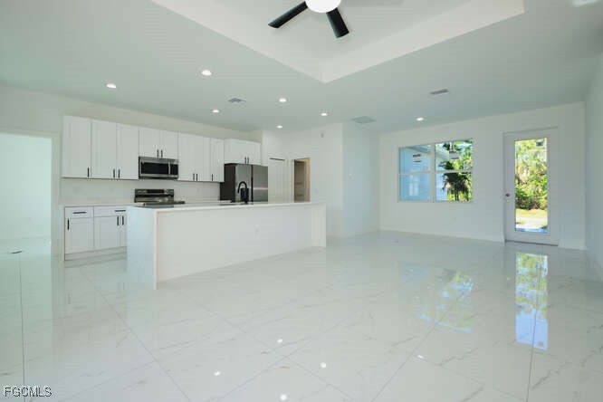 3421 55th Street West Lehigh Acres, FL 33971 - Photo 9 of 38 a large white kitchen with kitchen island a sink stainless steel appliances and cabinets