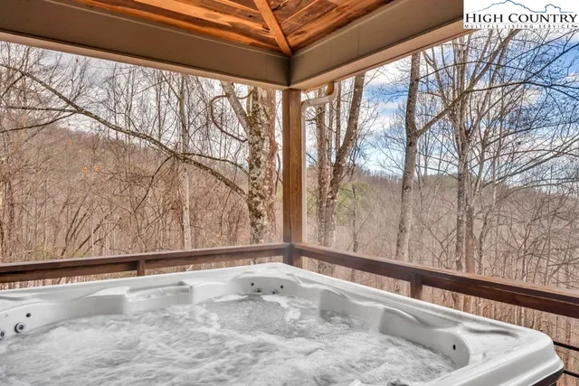 a view of a house with a wooden deck and a forest