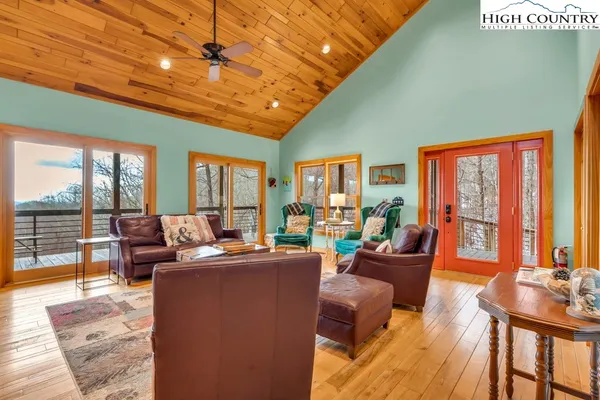 a living room with furniture a flat screen tv and floor to ceiling windows