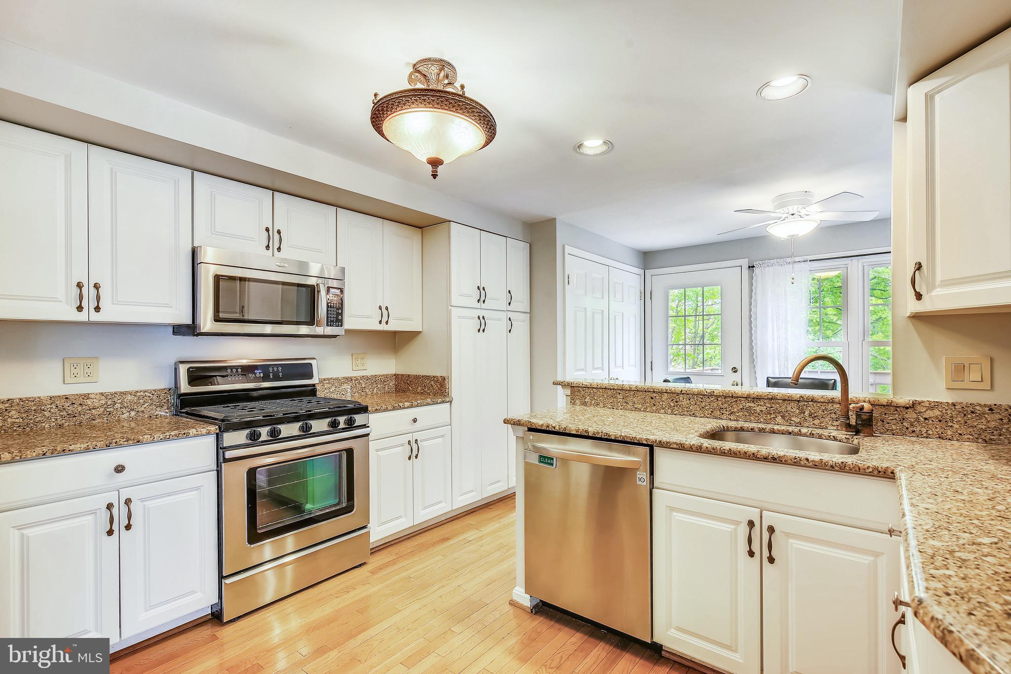 1530 Deer Point Way Reston, VA 20194 - Photo 8 of 42 a kitchen with stainless steel appliances granite countertop white cabinets a sink a stove a microwave and wooden floors