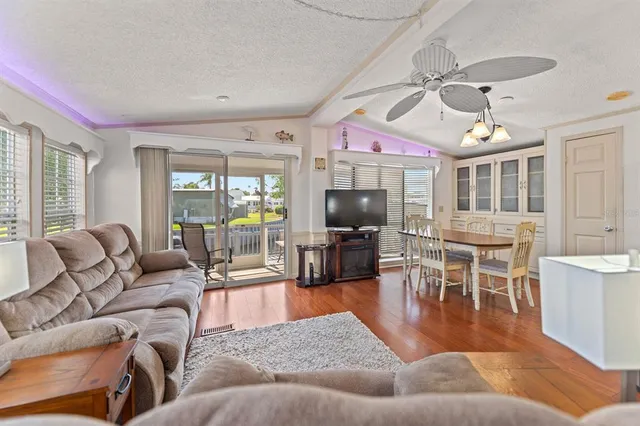 a living room with furniture a flat screen tv and kitchen view