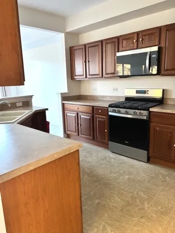 a kitchen with stainless steel appliances granite countertop a stove a sink and a microwave