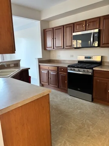 a kitchen with stainless steel appliances granite countertop a stove a sink and a microwave
