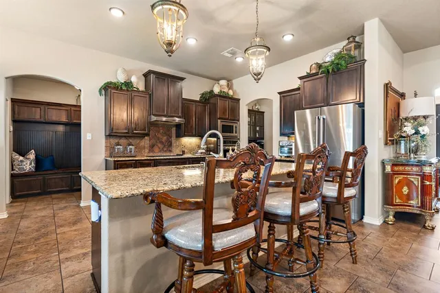 a kitchen with stainless steel appliances granite countertop a refrigerator a stove and a sink with granite countertops