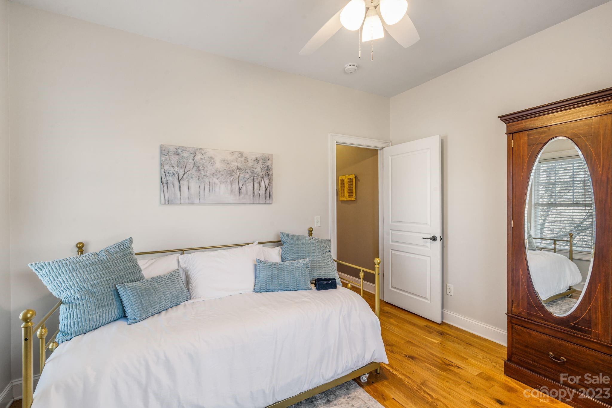874 Burney Mountain Road Fletcher, NC 28732 - Photo 23 of 37 a bedroom with a bed a mirror on the dresser and a chandelier