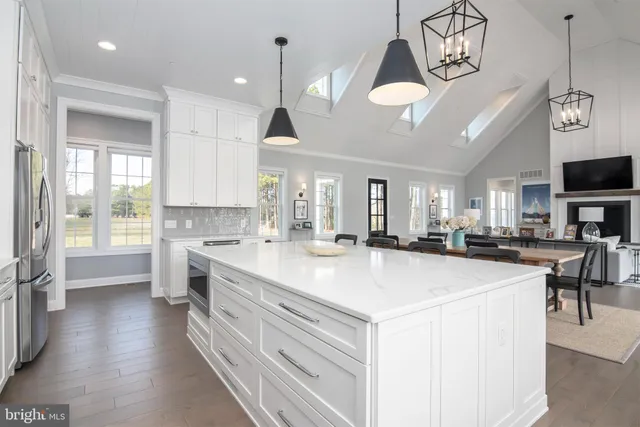 a large white kitchen with lots of counter space a sink appliances and white cabinets