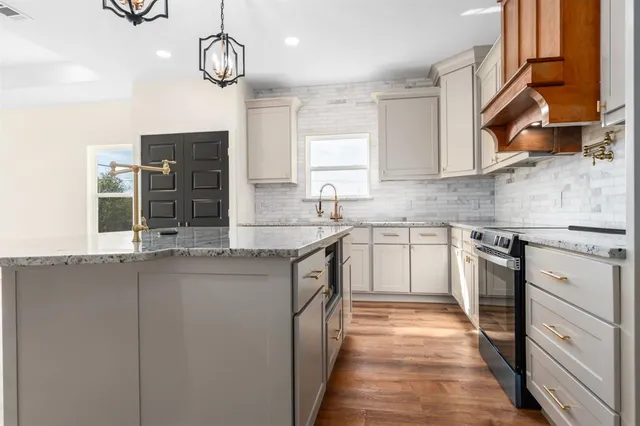 a kitchen with stainless steel appliances granite countertop a sink and dishwasher a stove top oven with wooden floor