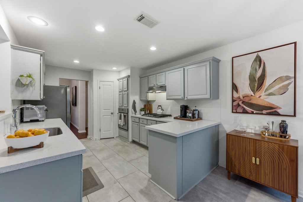 6925 Auckland Drive Austin, TX 78749 - Photo 8 of 29 Designed for daily living and easy entertaining, the soft sage green kitchen features quartz countertops, porcelain tile, and a clean, modern aesthetic.