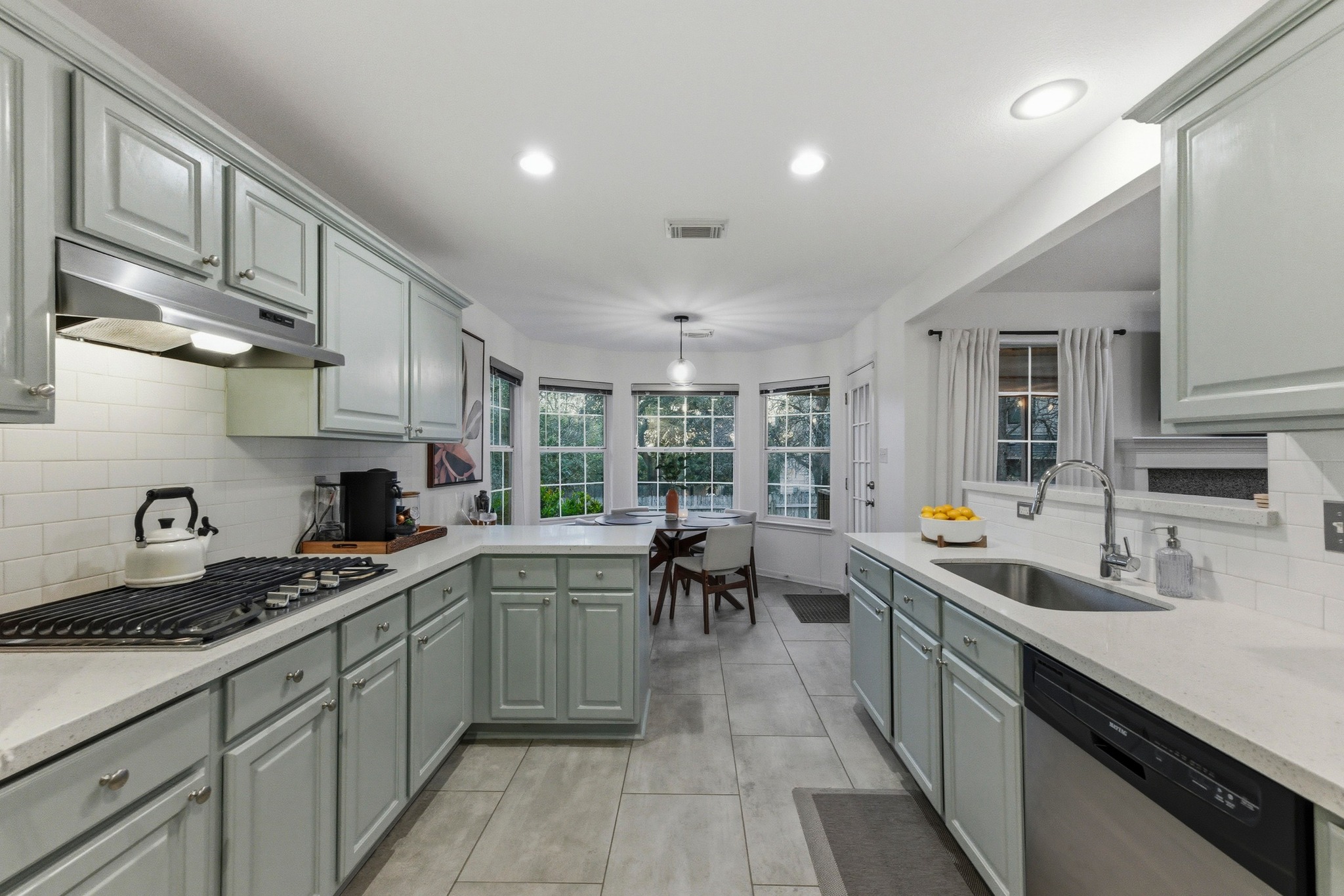 6925 Auckland Drive Austin, TX 78749 - Photo 10 of 29 Kitchen with decorative backsplash, stainless steel appliances, a peninsula, and hanging light fixtures