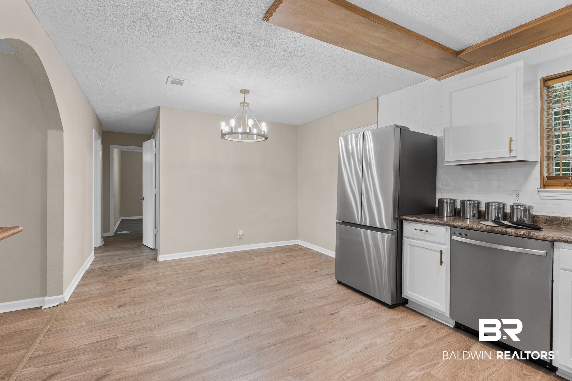 1560 Military Road Mount Vernon, AL 36560 - Photo 6 of 26 Open-concept kitchen and dining area featuring wood-finish flooring, white cabinetry with gold-tone hardware, and a stainless steel refrigerator and dishwasher