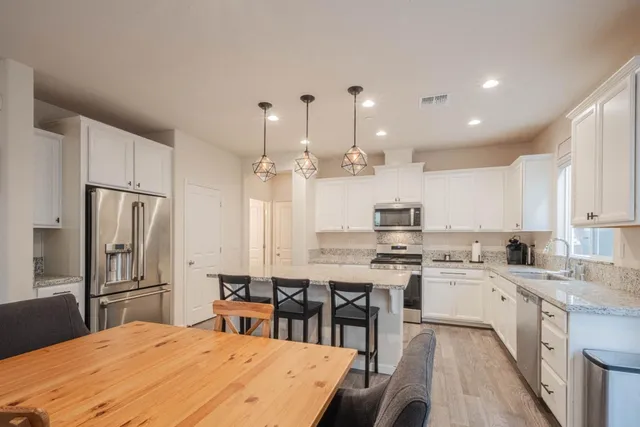 a kitchen with stainless steel appliances granite countertop a stove top oven a refrigerator a sink and dishwasher with wooden floor