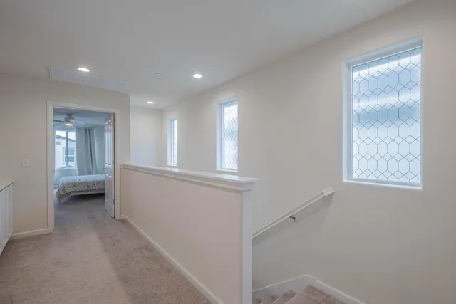 a view of hallway with window and wooden floor