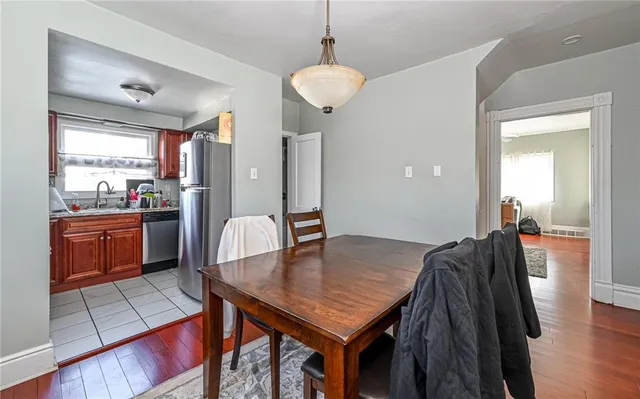 a kitchen with stainless steel appliances granite countertop a stove top oven a sink a dining table and chairs with wooden floor