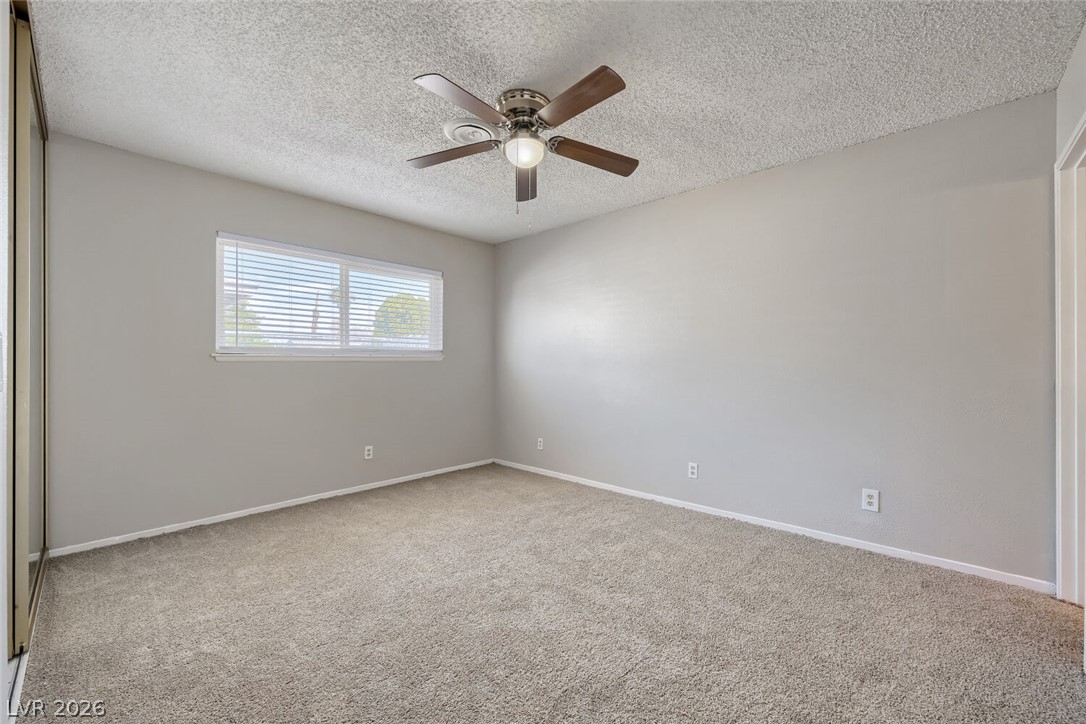 6321 Portola Road Las Vegas, NV 89108 - Photo 18 of 29 A well-lit bedroom offering plush carpeting and a convenient ceiling fan for year-round comfort.