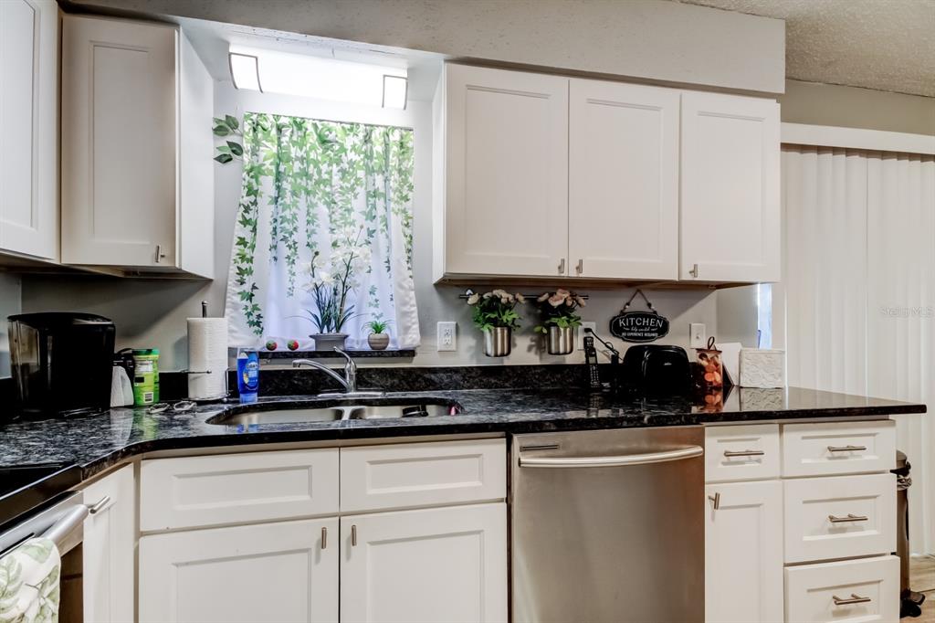 39748 Meadowood Loop Zephyrhills, FL 33542 - Photo 32 of 40 a kitchen with stainless steel appliances granite countertop a sink a stove and a white cabinets