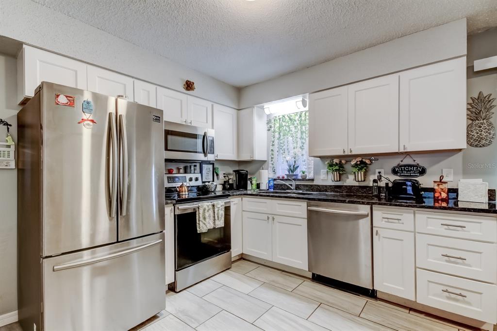 39748 Meadowood Loop Zephyrhills, FL 33542 - Photo 4 of 40 a kitchen with white cabinets stainless steel appliances and a window