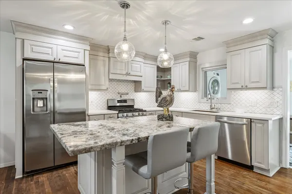a kitchen with stainless steel appliances granite countertop a kitchen island hardwood floor and a sink