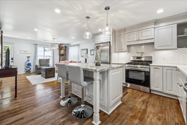 a kitchen with stainless steel appliances a stove a sink dishwasher a refrigerator and white cabinets with wooden floor