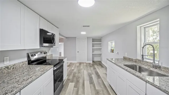 a kitchen with granite countertop a sink a stove and cabinets
