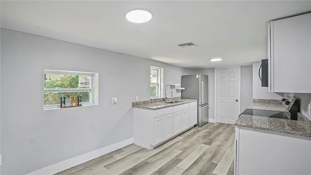 a large kitchen with granite countertop a stove and a sink