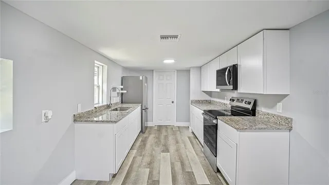 a kitchen with granite countertop a stove top oven sink and cabinets