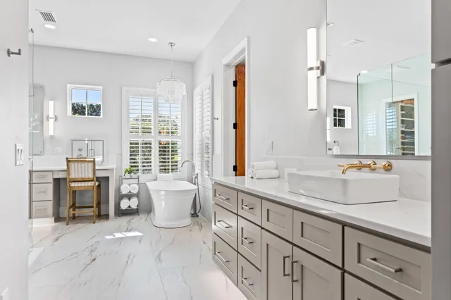 a spacious bathroom with double vanity a mirror a lamp and a bathtub