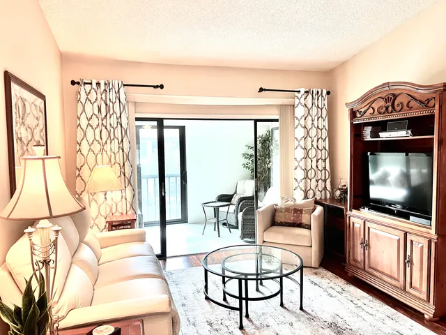 a living room with furniture a flat screen tv and a floor to ceiling window