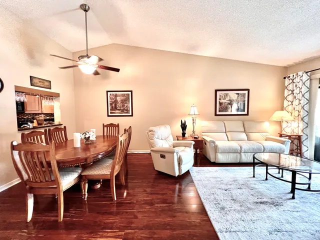 a dining room with wooden floor a chandelier fan a wooden table and chairs