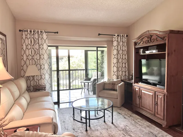 a living room with furniture a flat screen tv and a floor to ceiling window