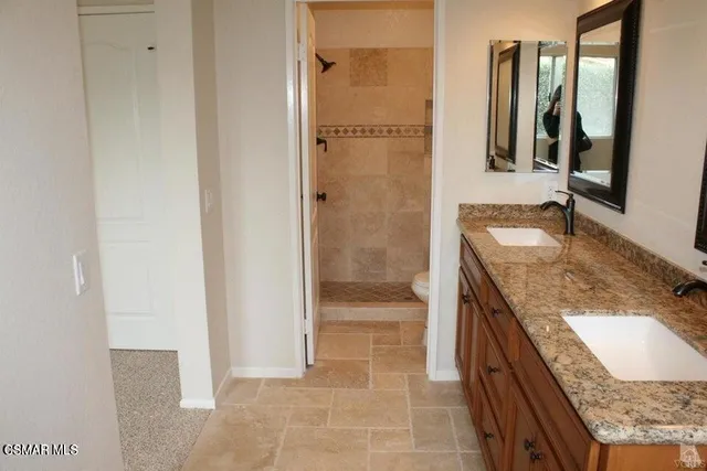 a bathroom with a granite countertop sink a mirror and shower