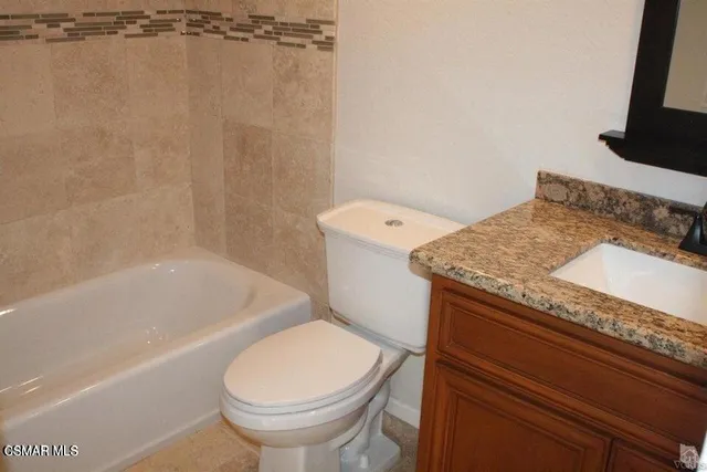 a bathroom with a granite countertop sink toilet and bathtub