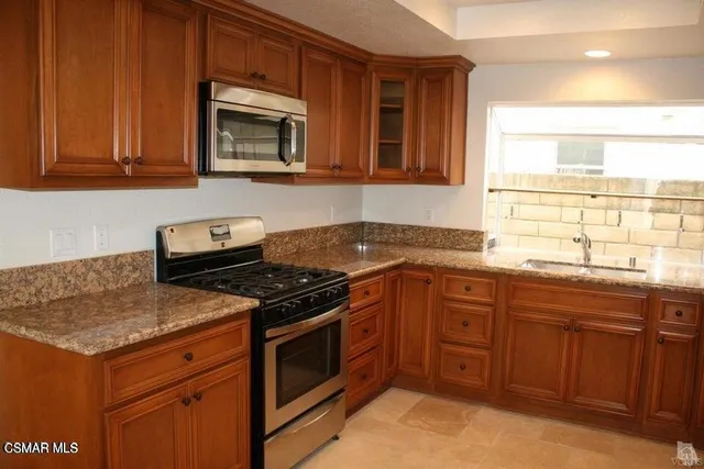 a kitchen with granite countertop a stove top oven microwave and cabinets