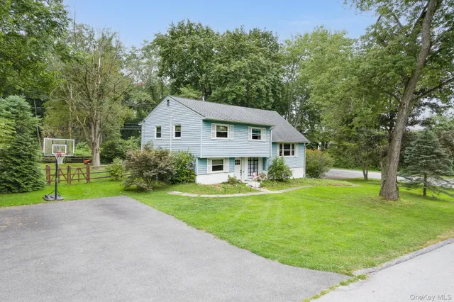 a front view of a house with garden and trees