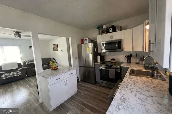 a kitchen with stainless steel appliances a refrigerator sink and wooden floor