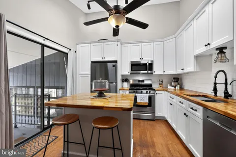 a kitchen with stainless steel appliances granite countertop a dining table chairs refrigerator and microwave