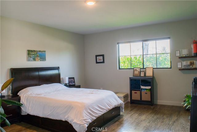 a view of swimming pool with lawn chairs plants and large trees