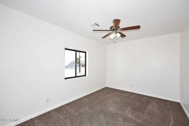 an empty room with a window and a ceiling fan