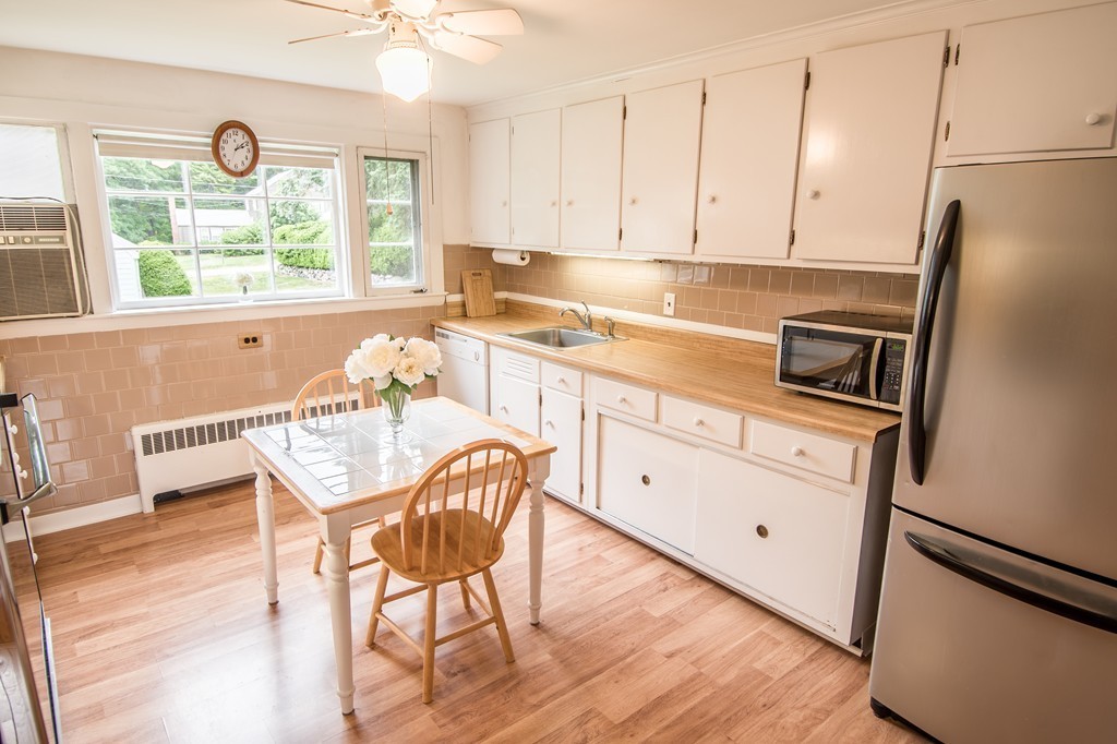 79 Park Street Dedham, MA 02026 - Photo 3 of 29 a kitchen with stainless steel appliances granite countertop a stove a refrigerator a dining table and chairs with wooden floors