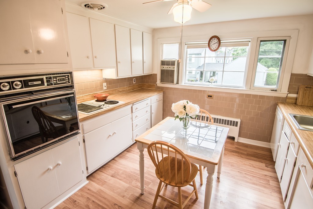79 Park Street Dedham, MA 02026 - Photo 4 of 29 a kitchen with stainless steel appliances granite countertop a stove a sink a dining table and chairs with wooden floor